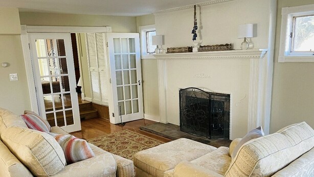 A living room with two beige sofas, a fireplace, and a staircase leading to another room.