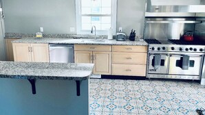 A kitchen with granite countertops, a stainless steel range, and a patterned tile floor.
