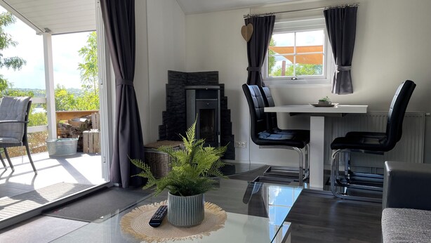 Una sala moderna con una mesa de vidrio, sillas negras, una chimenea y vistas al exterior.