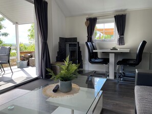 Una sala moderna con una mesa de vidrio, sillas negras, una chimenea y vistas al exterior.