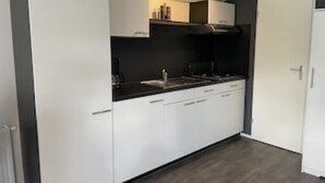 Una cocina moderna con armarios blancos, una encimera negra y una estufa integrada.