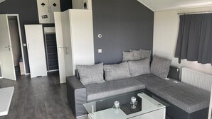 Una sala de estar moderna con un sofá modular gris, una mesa de centro de vidrio y una pared de acento oscura.