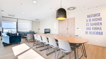 Uma sala de reunião moderna com uma mesa comprida, cadeiras e uma luminária pendente grande.
