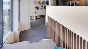A modern interior with a staircase, patterned wall, and ceiling lights. -  Livensa Living Studios Madrid Alcobendas (Alcobendas)