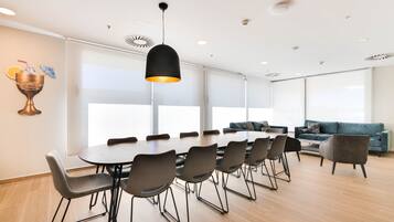 Une salle de réunion moderne, dotée d’une grande table, de chaises et d’un luminaire suspendu.