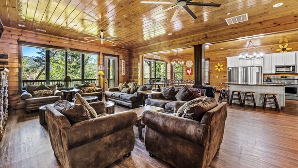 A spacious living area with leather sofas, wooden flooring, and a kitchen area with modern appliances.