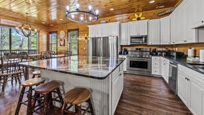 A spacious kitchen with white cabinets, stainless steel appliances, and a large island with stools.