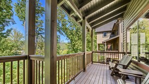 A wooden deck with a railing, wooden chairs, and a view of a house.