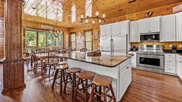 Ett rymligt kök med träskåp, en stor köksö med barstolar och ett kylskåp i rostfritt stål.