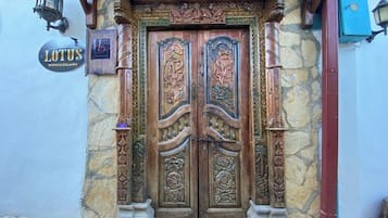 Traditional stone structure with a beautifully carved wooden door and stone pillars.