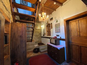 A rustic interior with a wooden staircase, a chandelier, a stone wall, and a red rug. - Şirince Lotus Konakları (Selçuk)