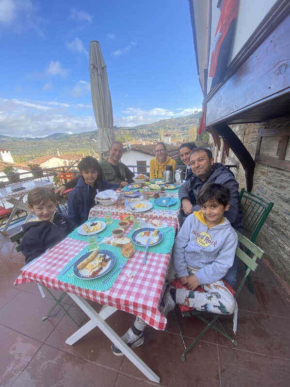 A group of people seated at an outdoor table with a red and white checkered tablecloth, enjoying a meal. - Şirince Lotus Konakları (Selçuk)