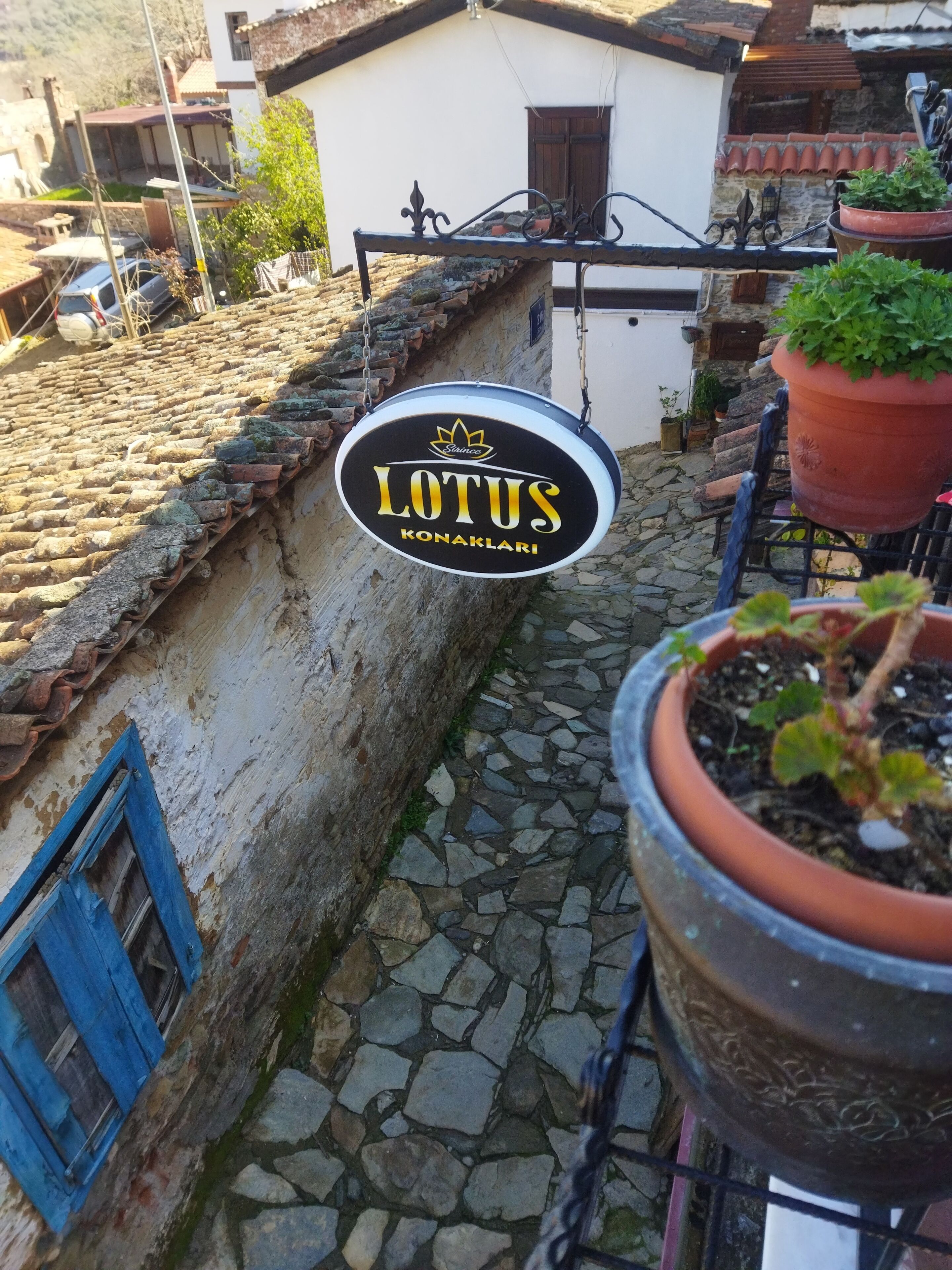 Une enseigne indiquant « LOTUS KONAKLARI » est suspendue au-dessus d’un sentier pavé de pierres.