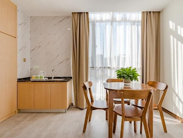 A modern kitchen with a marble backsplash, wooden cabinets, and a dining area with a table and chairs. - Greentree Inn Taian High Speed Railway Station Lingshan Street (Tai'an)