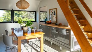 Eine moderne Küche mit einem Holzespeisetisch, Stühlen und einer Pendelleuchte.