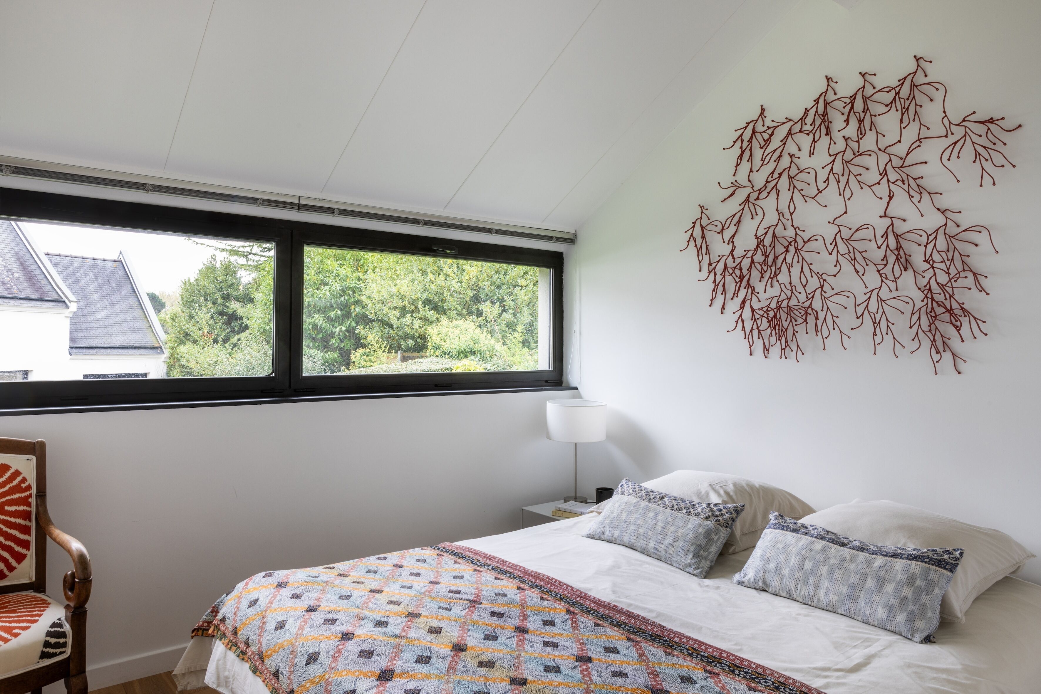 Une chambre à coucher comprenant un lit, une fenêtre, une table de chevet et une œuvre d’art murale.