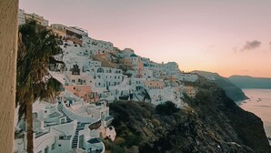 A coastal town with white buildings, steep cliffs, and a calm sea. - Elias Cave Oia 270o Caldera View  Bioclimatic Eco House Santorini  (Οία)