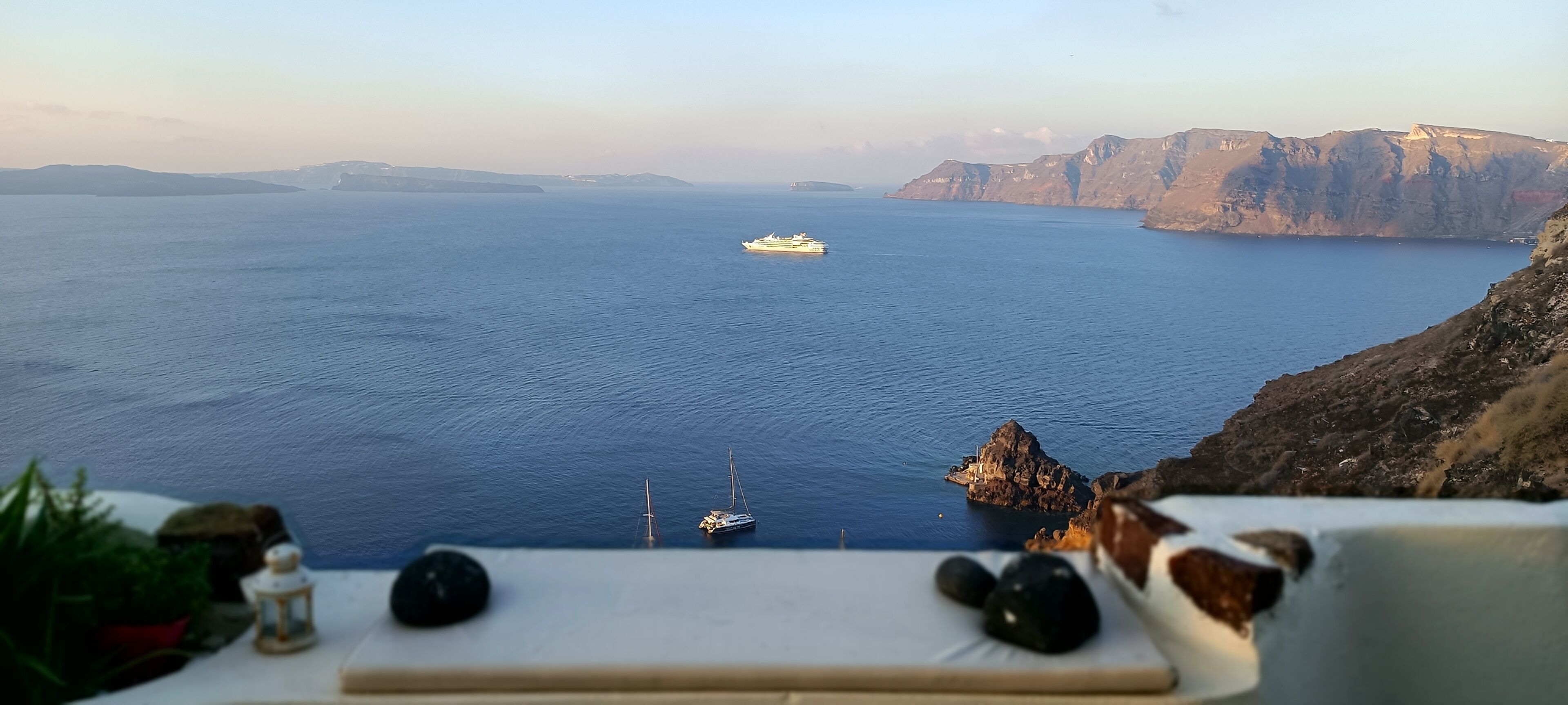 Vue d’une zone côtière avec une étendue d’eau importante, un yacht et des falaises rocheuses.