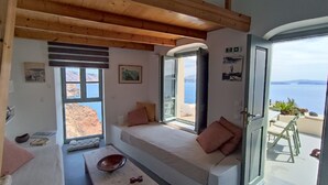A cozy room with a large window, a wooden ceiling, and a view of the sea. - Elias Cave Oia 270o Caldera View  Bioclimatic Eco House Santorini  (Οία)