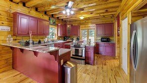 Cocina de cabaña de madera con una isla central, electrodomésticos de acero inoxidable y armarios rojos.