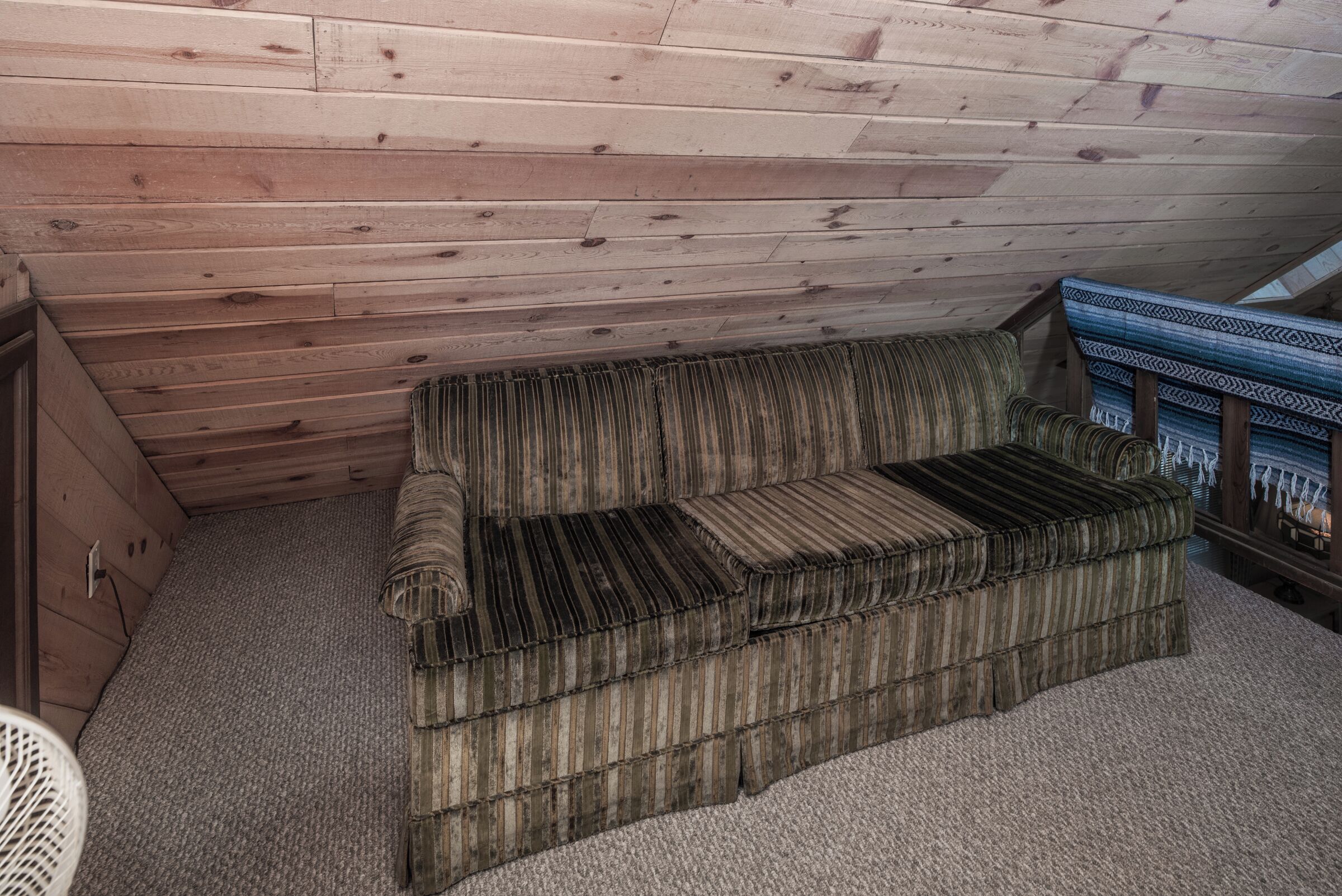 A wooden ceiling with a sofa and a patterned rug.