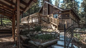 A wooden cabin with a wooden staircase leading to a deck.