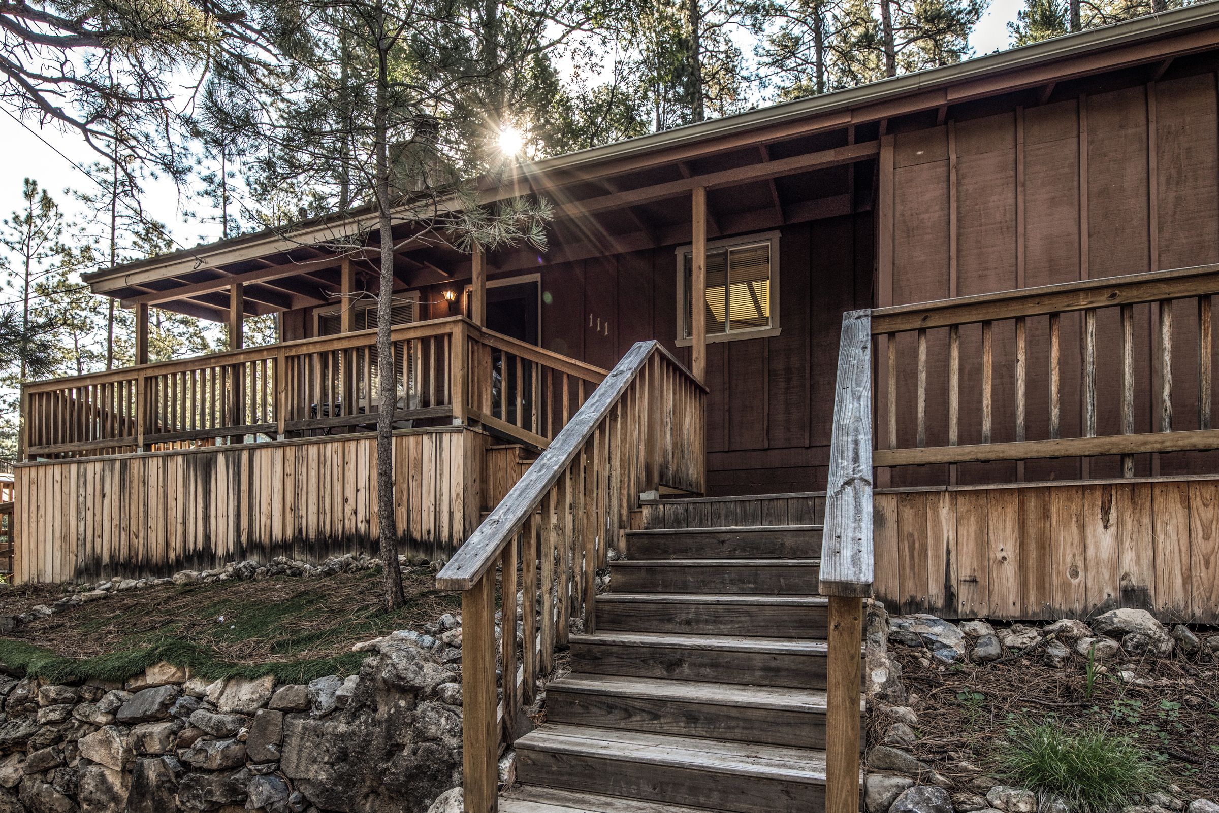 A wooden cabin with a wooden staircase leading to a porch.