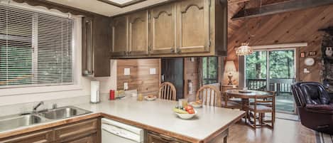 A kitchen with wooden cabinets, a dishwasher, and a dining area with a table and chairs.