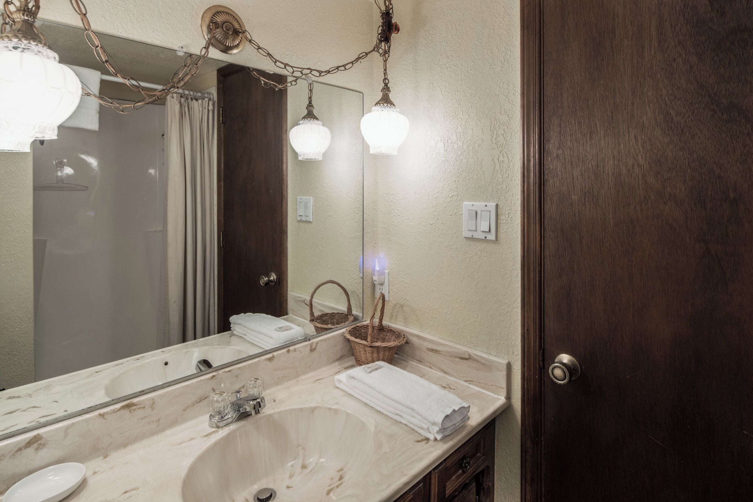 A bathroom with a large mirror, a sink, and a door.