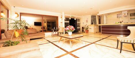 Vestíbulo de hotel con mostrador de recepción, zona de estar y una planta grande.