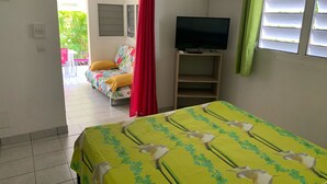 Une chambre d’hôtel avec un lit, un téléviseur posé sur un meuble, une fenêtre avec des stores et une vue sur l’extérieur.