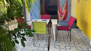 Une pièce comprenant une table, des chaises, un hamac et une porte donnant sur une autre pièce.