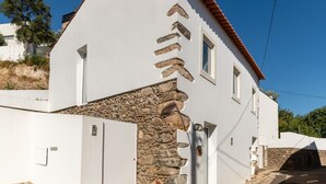 Un bâtiment blanc avec une façade en pierre et un toit recouvert de tuiles rouges.