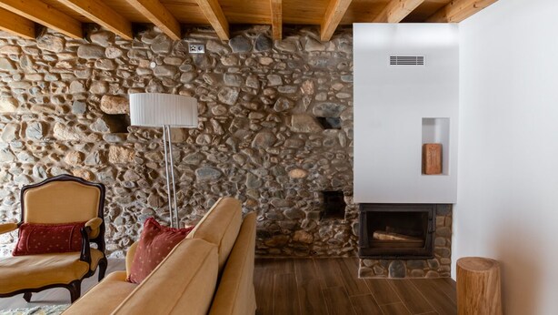 Un salon chaleureux avec un mur en pierre, une cheminée, un canapé et un lampadaire.