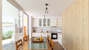 Une cuisine moderne avec des meubles blancs, une table à manger en bois et une cloison en verre.