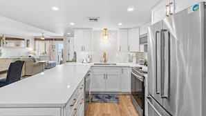 A modern kitchen with white cabinetry, stainless steel appliances, and a central island.