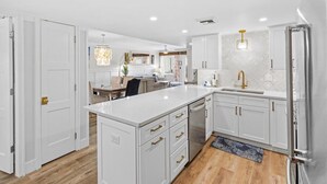 A modern kitchen with white cabinetry, a central island, and stainless steel appliances.
