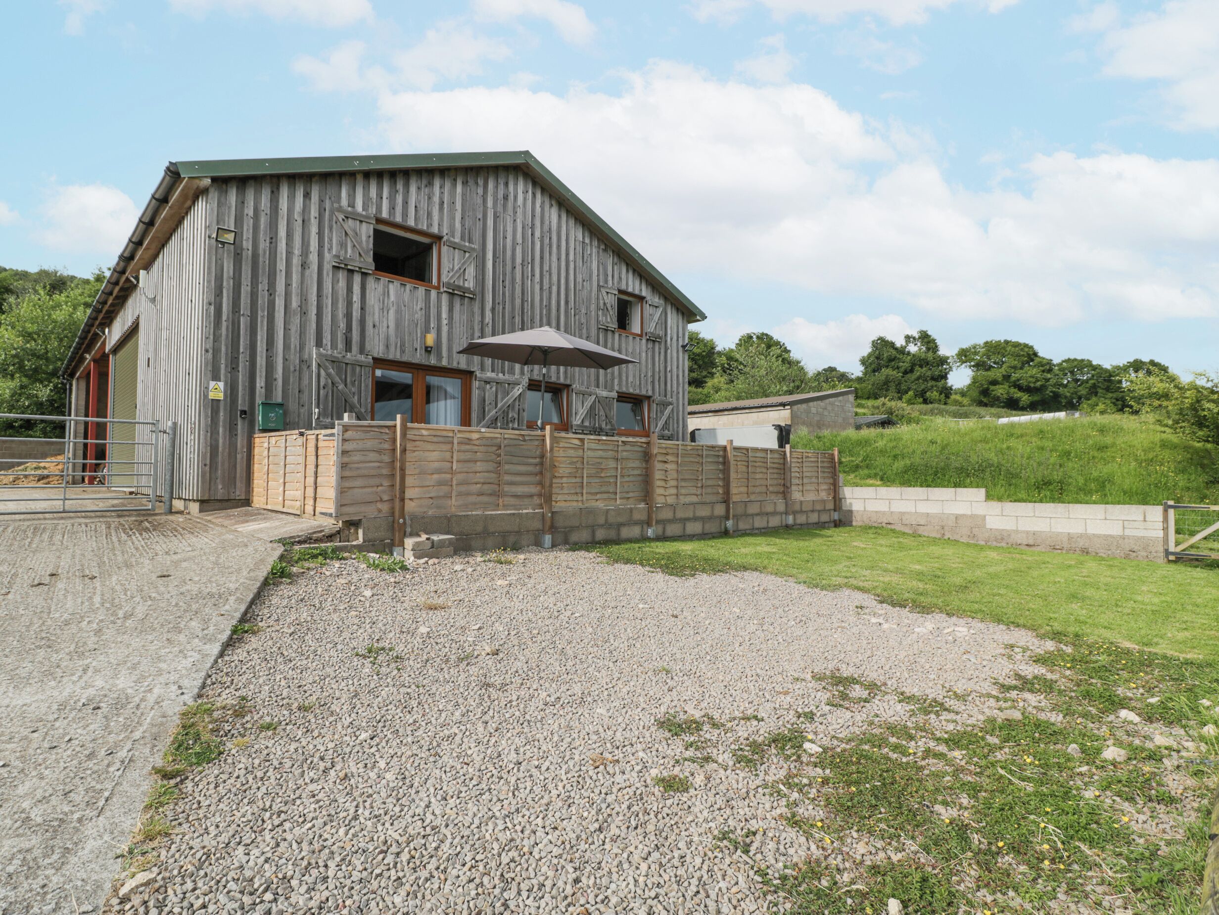Une grange rustique avec une allée en gravier et une clôture en bois.