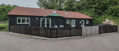 Une maison à deux étages avec un toit recouvert de tuiles rouges, une clôture en bois et une allée pavée.