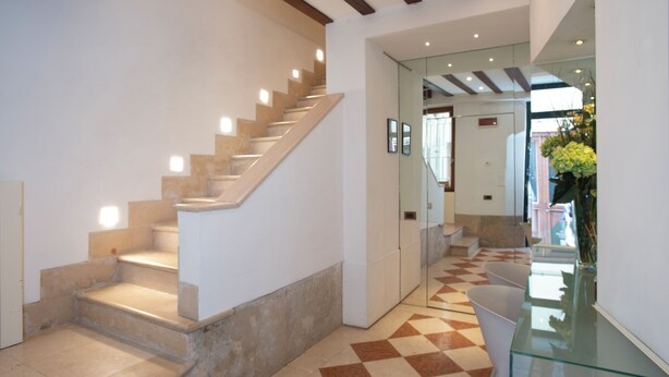 Un intérieur moderne avec un escalier, une table en verre et un sol à carreaux.