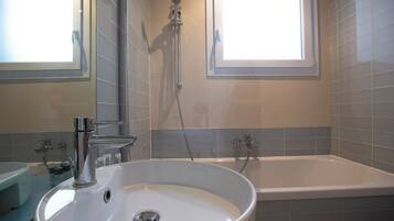 A bathroom with a white sink, a bathtub, and a shower.