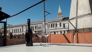 Une bouteille et un verre à vin vide sont posés sur une table, avec en arrière-plan la vue d’un bâtiment historique.
