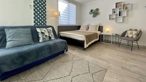 Ein modernes Schlafzimmer mit Bett, einer Couch, einem Sessel und einem kleinen Tisch.