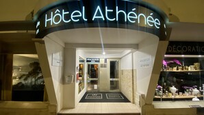 Der Eingang zum Hotel Athénée mit deutlicher Beschilderung, einem gefliesten Boden und einer Glastür.