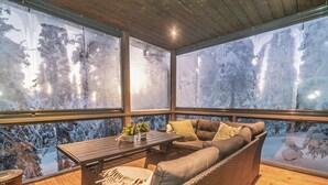 A covered outdoor seating area with a wooden floor, a sofa, a table, and a bench. - Rukan rinnemaa a by Interhome (Kuusamo)