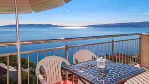 A balcony with a table and chairs, overlooking a large body of water and distant mountains. - Apartment Elena by Interhome (Senj)