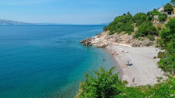 A beach with clear blue water, rocky terrain, and greenery. - Apartment Elena by Interhome (Senj)