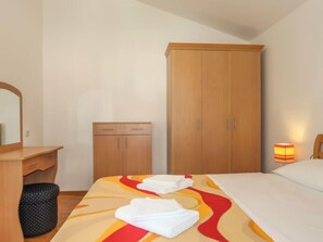Ein Hotelzimmer mit einem Bett, einem Holzschrank, einem kleinen Schreibtisch mit Spiegel und einer Nachttischlampe.