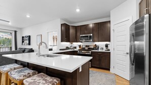 A modern kitchen with dark wood cabinets, stainless steel appliances, and a central island with bar stools.