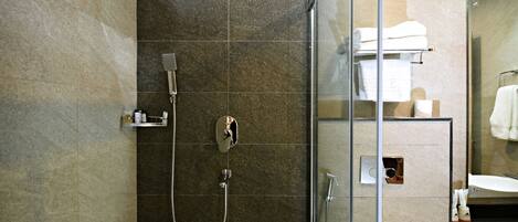 A modern bathroom with a glass-enclosed shower, a white toilet, and a sink with a mirror above it.